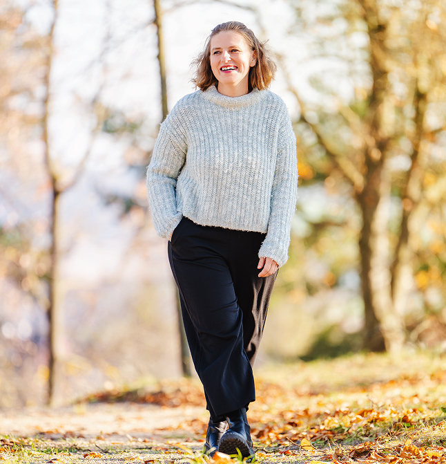 Alexandra spaziert den Wald entlang und lächelt