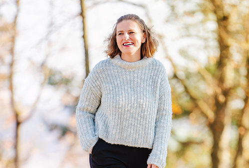 Alexandra spaziert den Wald entlang und lächelt